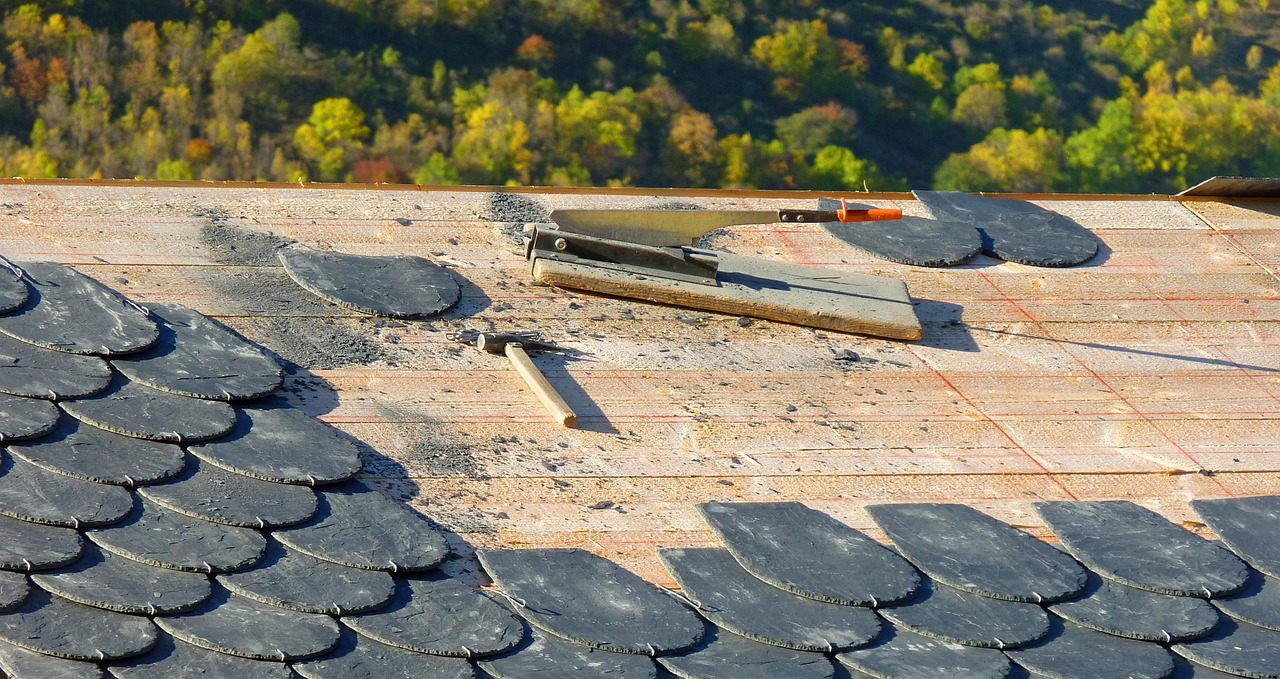 Roofer installing asphalt shingles on residential roof during replacement work